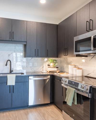 The interior view of The Row apartments kitchen with dark wood cabinets and light wood flooring at The Row in Raleigh,North Carolina