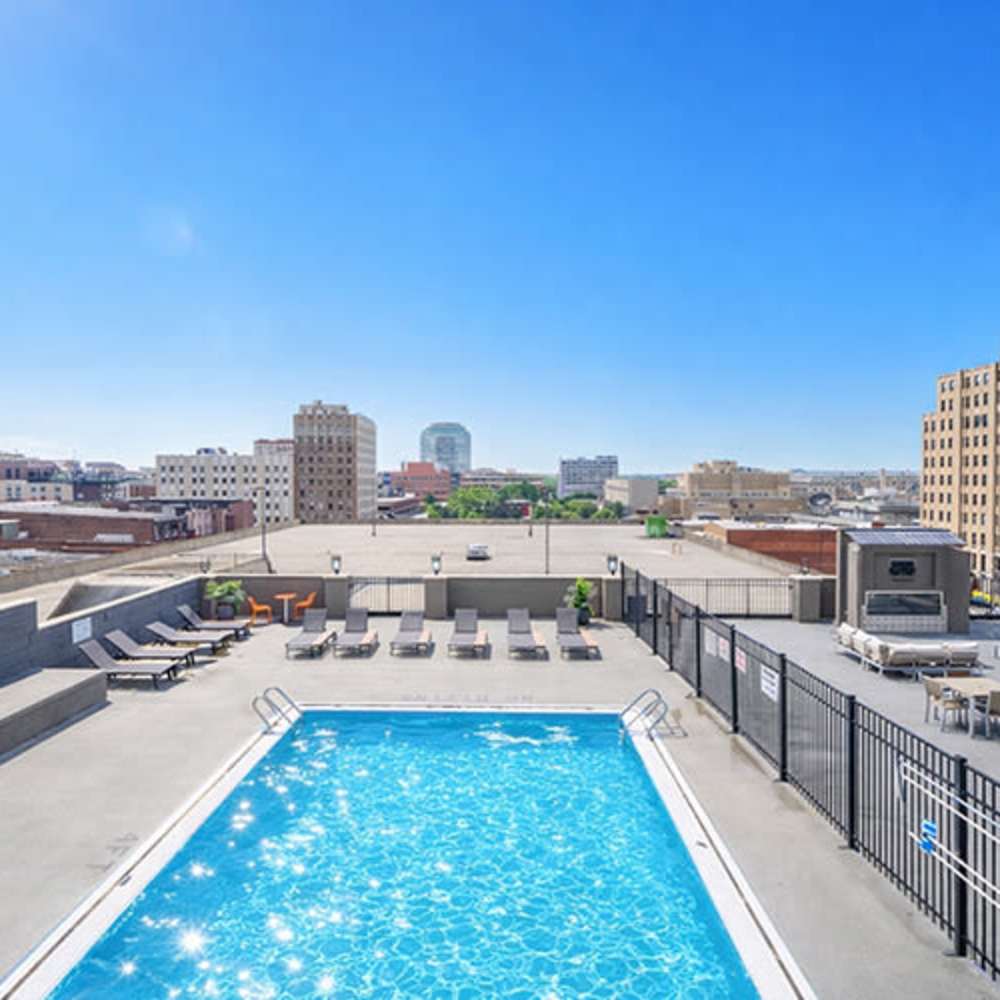 Rooftop sparkling pool with lounge chairs and city skyline in the background at Flats on Fifth in Louisville, Kentucky