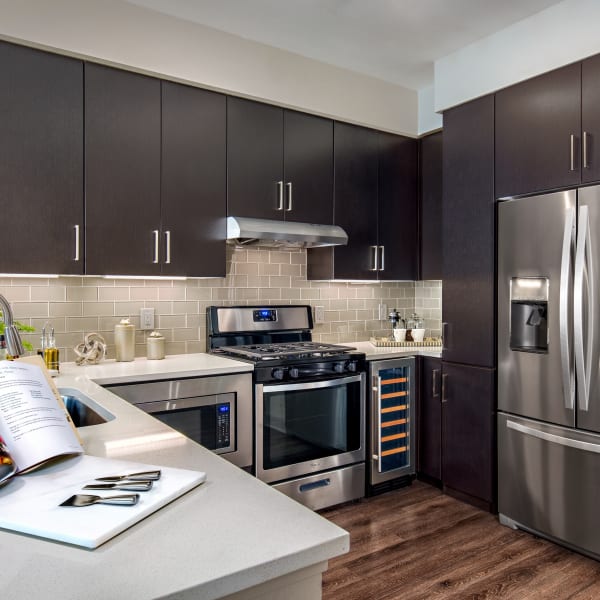 Gourmet kitchen with dark wood cabinetry and stainless-steel appliances in a model home at The Core Scottsdale in Scottsdale, Arizona