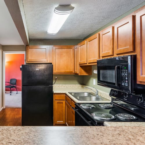Kitchen with black appliances and stainless-steel double sink at Monroe Terrace Apartments in Monroe, Ohio