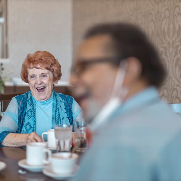 Two residents laughing while talking over coffee at The Castlewood Senior Living in Nixa, Missouri