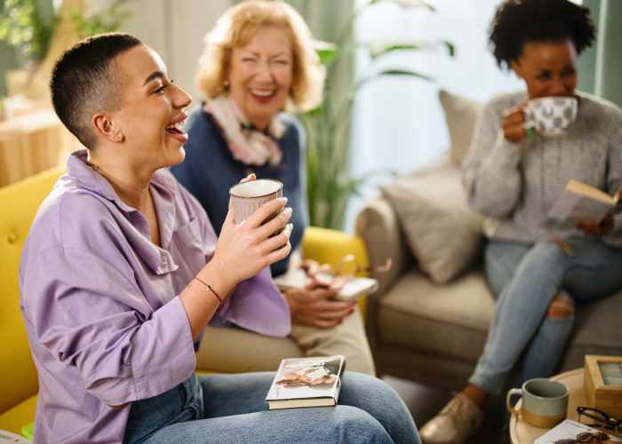 Residents having laugh over a cup of coffee in clubhouse at The Pointe at Loudon in Loudon, Tennessee, with lounge seating and relaxing outdoor area for residents.