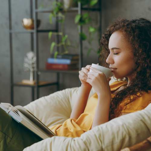 Woman sitting enjoying a cup of coffee while reading at Housing Hilltop in Tacoma, Washington