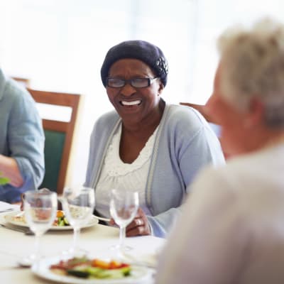 Residents laughing and smiling over a meal at Arbor Glen Senior Living in Lake Elmo, Minnesota