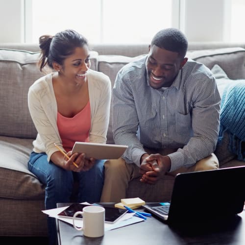 Residents looking at a tablet on a couch at Dahlgren Townhomes in Dahlgren, Virginia