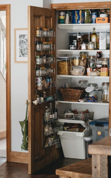 an open pantry door with an organizer on the back and floor storage items