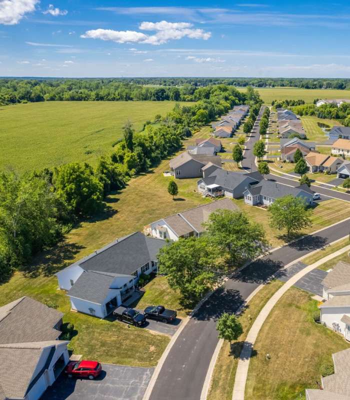 Aerial view of a suburban apartment community with well-maintained lawns and tree-lined streets at Unionville Station Townhomes in Hilton, New York