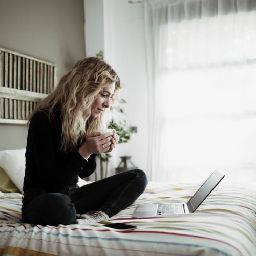 A resident setting on her bed and having her coffee at Forster Hills in Oceanside, California