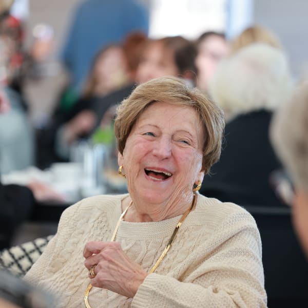 Two residents laughing while talking over coffee at The Wellington Senior Living in Liberty, Missouri