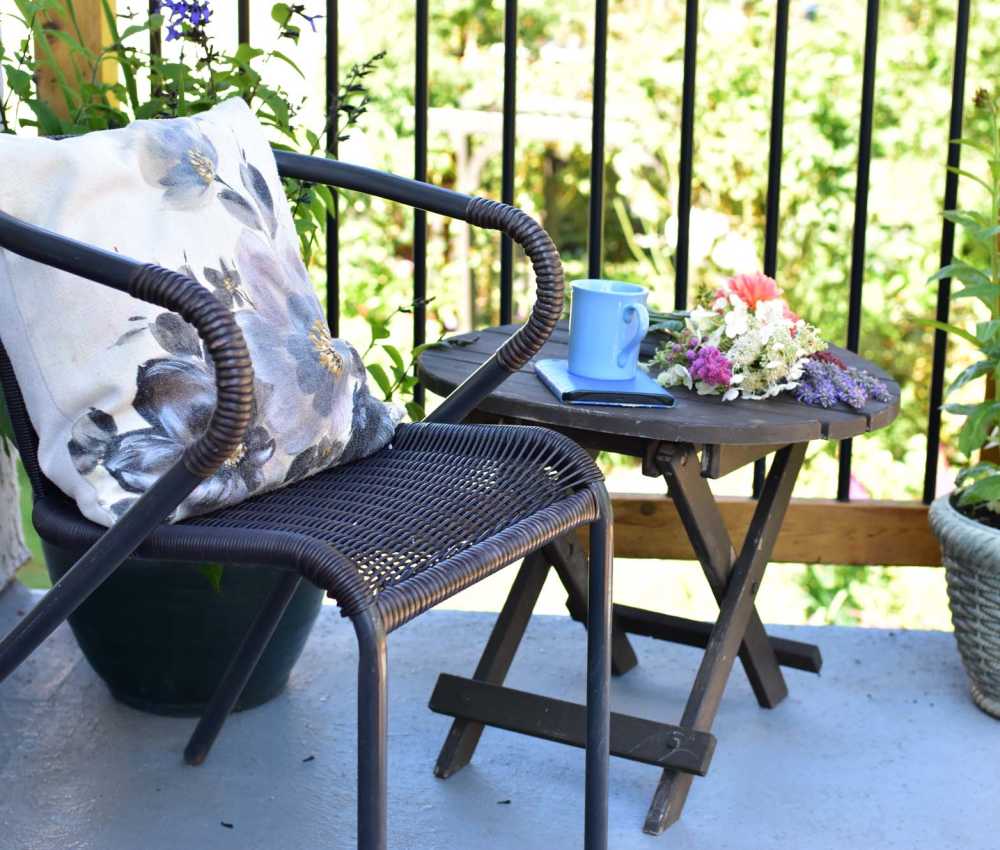Cozy balcony with a chair, small table, blue mug, and fresh flowers at South Oak in Ames, Iowa