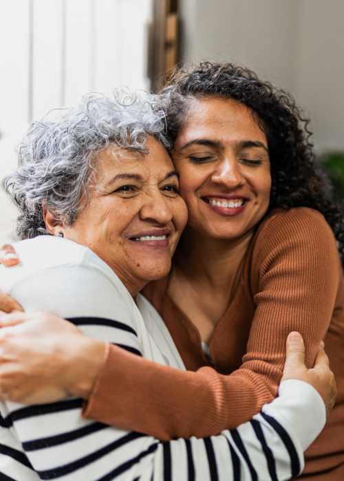 Resident woman hugging her mother in a living room of a model apartment at Falls Creek in Sanford, North Carolina