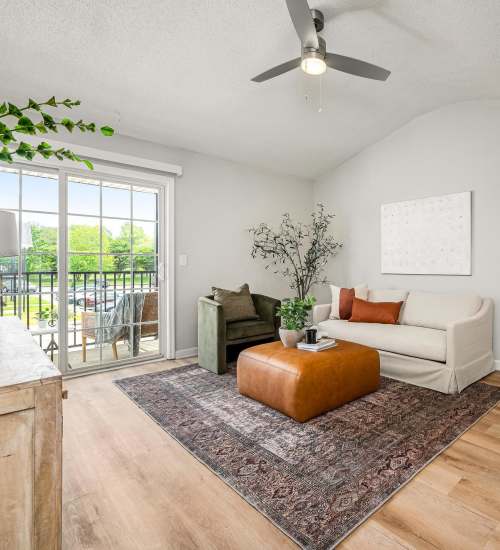 Spacious living room with couch, coffee table, wood-style flooring and open layout connecting to balcony at  Saddlebrook Apartments in Murfreesboro, Tennessee