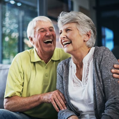 Resident couple sitting on the couch laughing at York Gardens in Edina, Minnesota