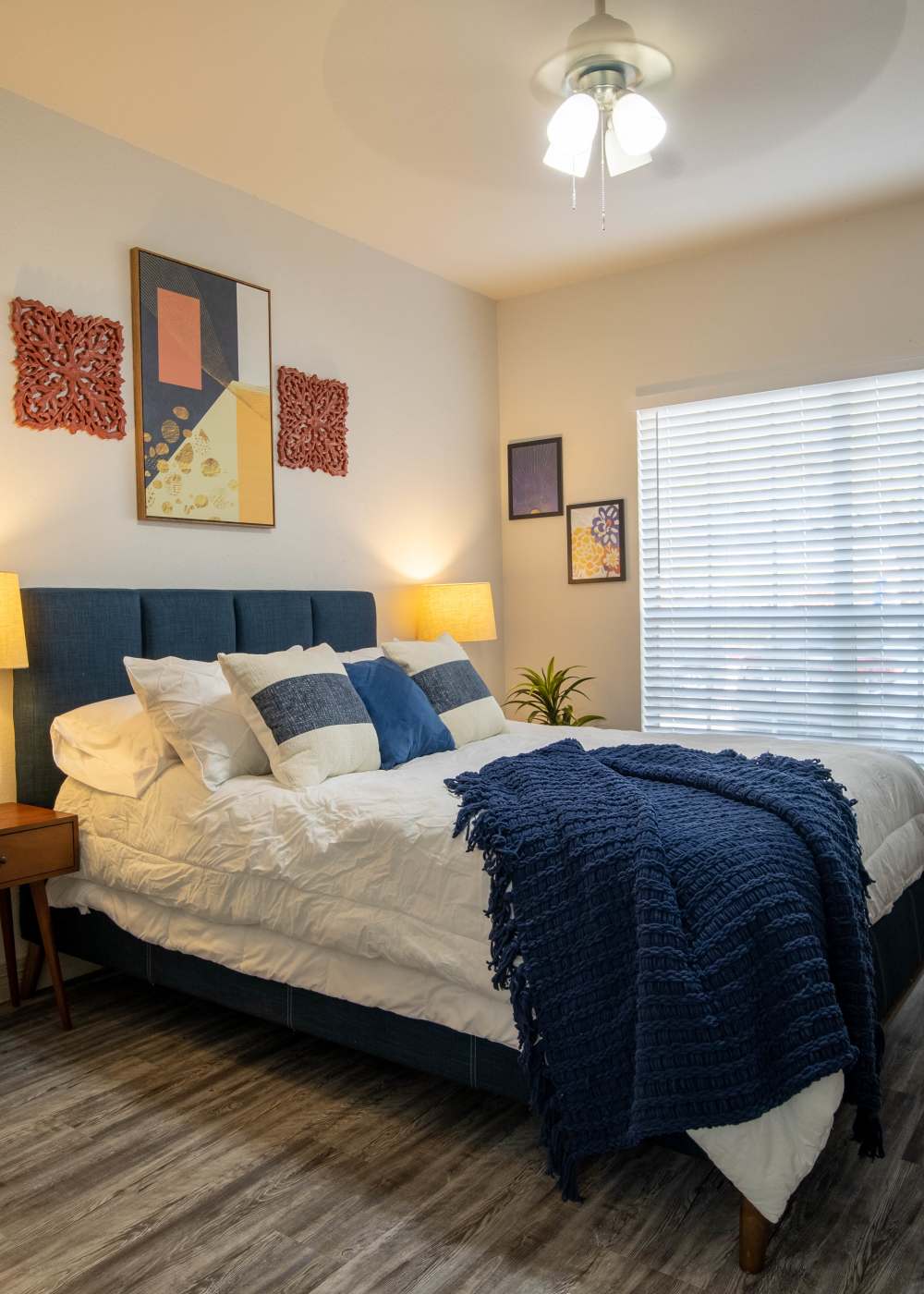 Modern bedroom with king size bed. wood-style flooring and large window at Brixton in Round Rock, Texas