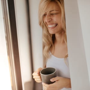 Resident enjoying her morning coffee while looking out the window of her home at Lofts at Pecan Ridge in Midlothian, Texas