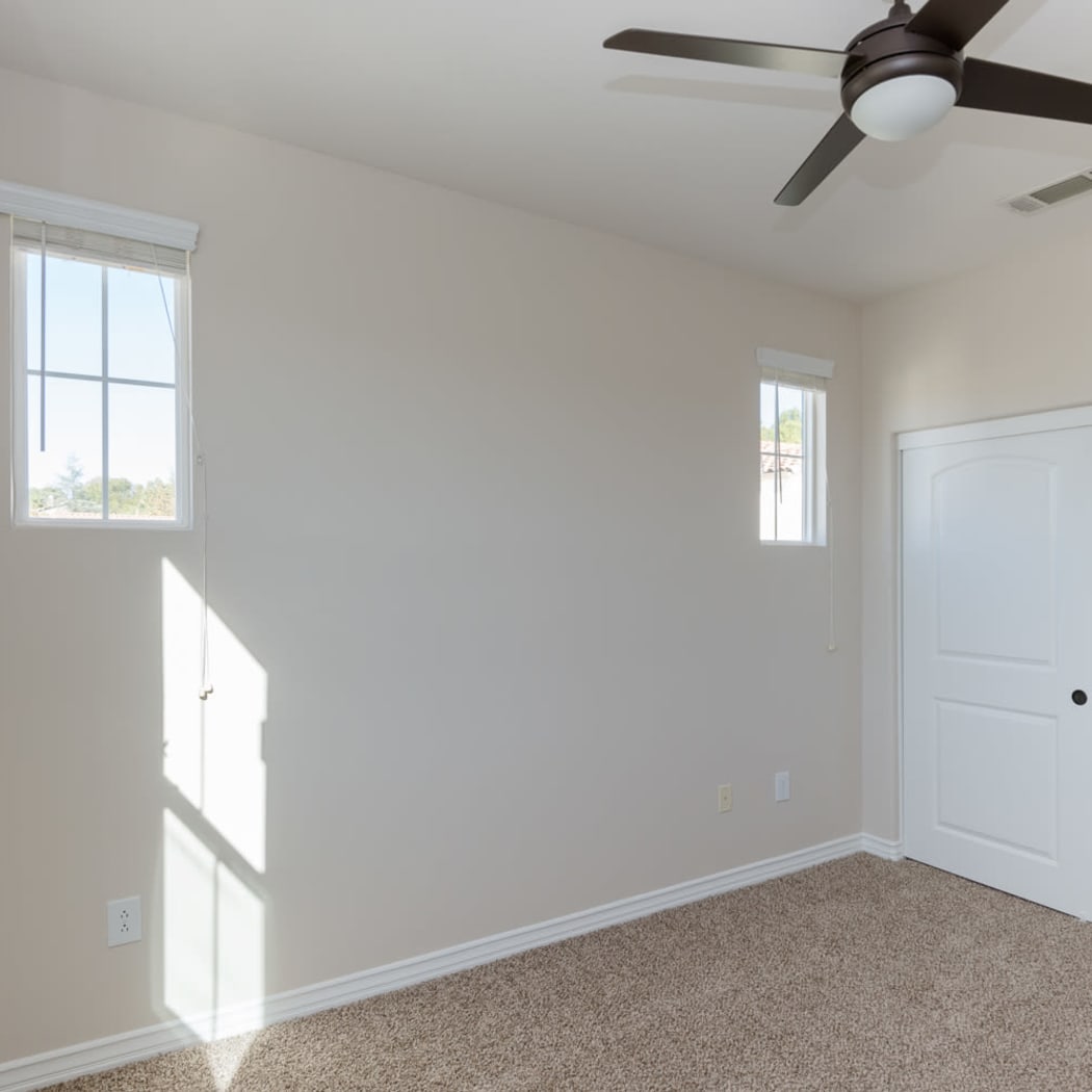 Bedroom with plush carpet and ceiling fan in model home at IMT Rancho Serrano Townhomes in Thousand Oaks, CA