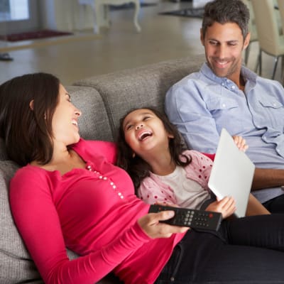 Two residents and their child laughing on the couch in their living room at Meriwether Landing in Joint Base Lewis-McChord, Washington