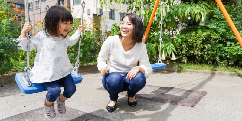 A mother watching a child play on the swings at a school near Home Terrace in San Diego, California