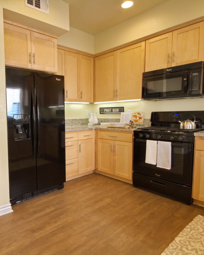Modern kitchen with hardwood floors and black appliances in model home at IMT Townhomes at Magnolia Woods in Sherman Oaks, CA