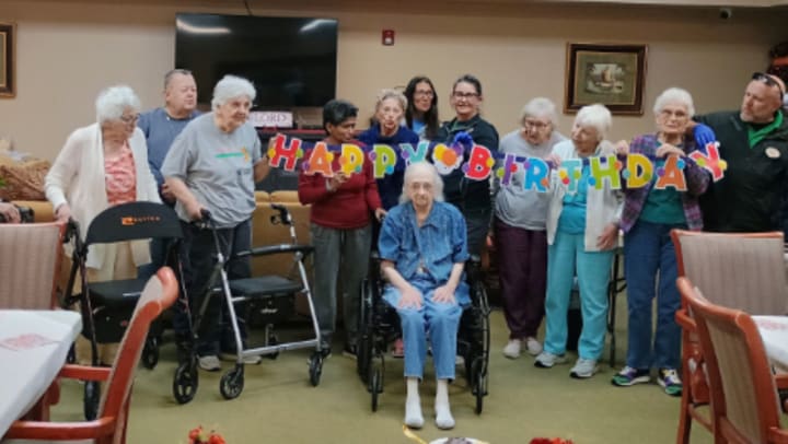 Sarah Cooper with Wesley Haven Villa friends and a Happy Birthday banner