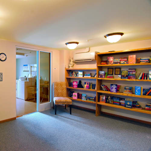 Bookshelves filled with various books and a chair at Richwood Greene Senior Living in Richwood, Ohio