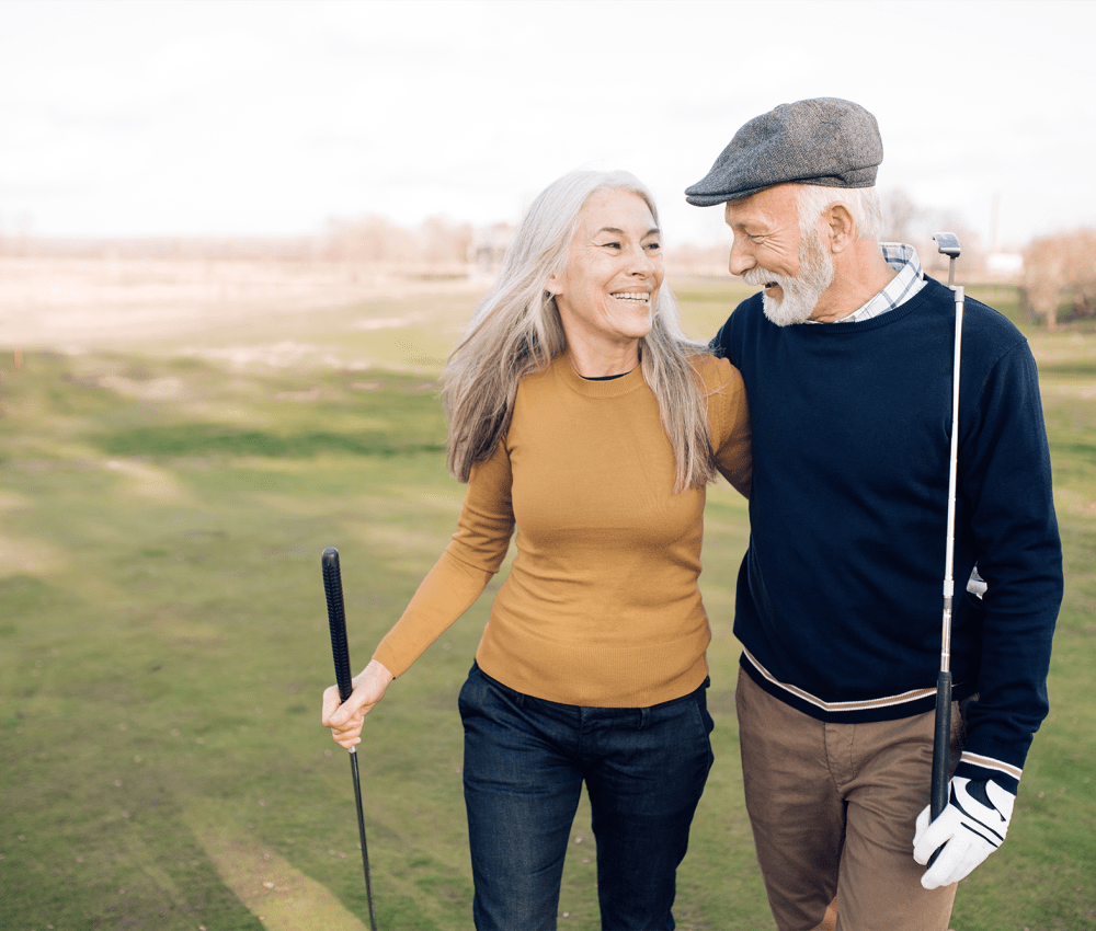 Resident couple holding golf clubs at Ravello 192 in Elkhorn, Nebraska