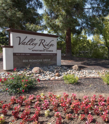 Apartment sign surrounded by flowers at Valley Ridge Apartment Homes in Martinez, California
