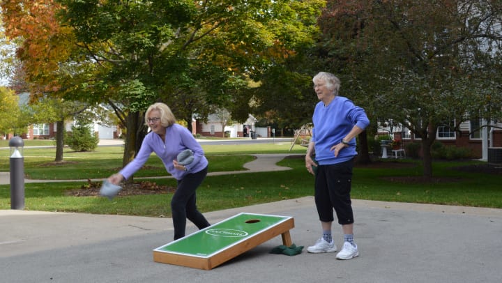 Image of two female residents competing in a cornhole tournament