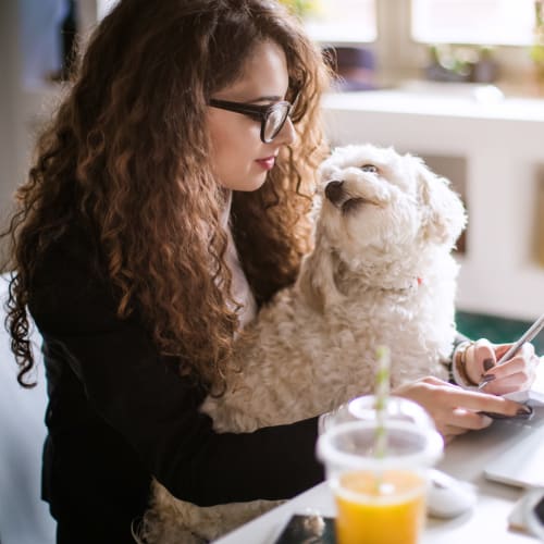 A resident with a dog in her lap looking at her phone at Columbia Colony in Patuxent River, Maryland