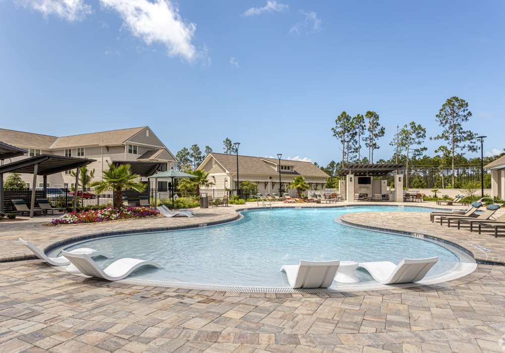 Resort-style swimming pool with lounge chair at Watersound Origins Crossings in Inlet Beach, Florida