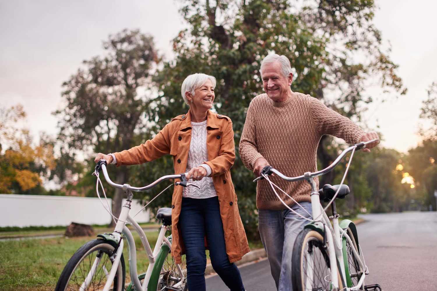Senior couple walking their bikes through the neighborhood at Ellsworth Commons Apartments in Greenville, North Carolina