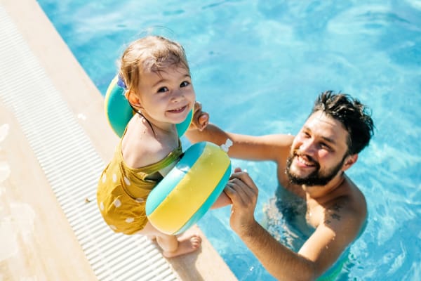 Resident and child in the pool at Sterling Pointe Apartments in Davis, California
