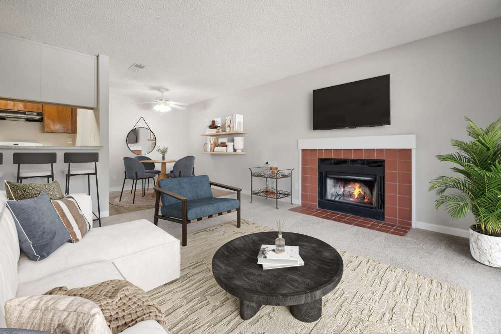 Open living room with carpet and a fireplace, dining area, and kitchen bar at Muirwood Apartment Homes in Martinez, California