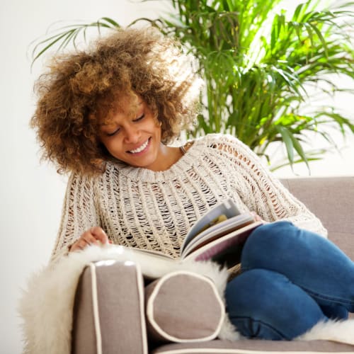 A resident sitting on a couch reading at Orleck Heights in San Diego, California