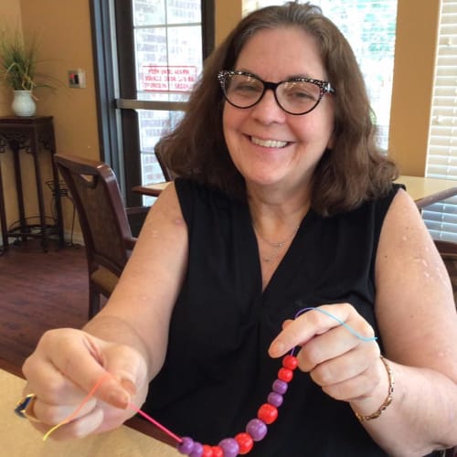 A seated resident smiling at Oxford Glen Memory Care at Carrollton in Carrollton, Texas