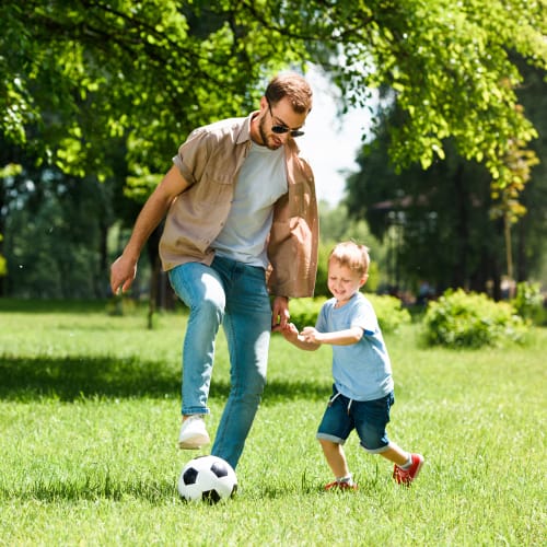 A father playing soccer with his son in a park near Eagleview in Joint Base Lewis McChord, Washington