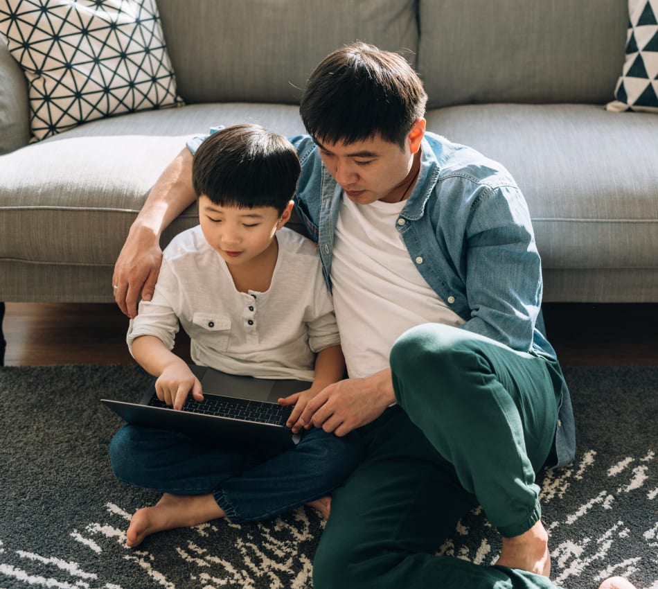 Father learning some tricks from his young son on a tablet device in their apartment at Terra Camarillo in Camarillo, California