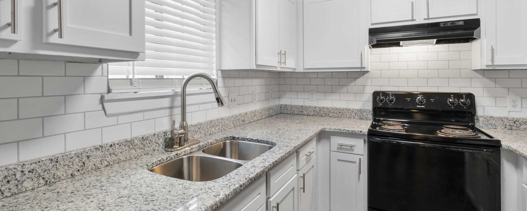 Bright, white kitchen area with black appliances in an apartment at Eagle's Edge in Indianapolis 