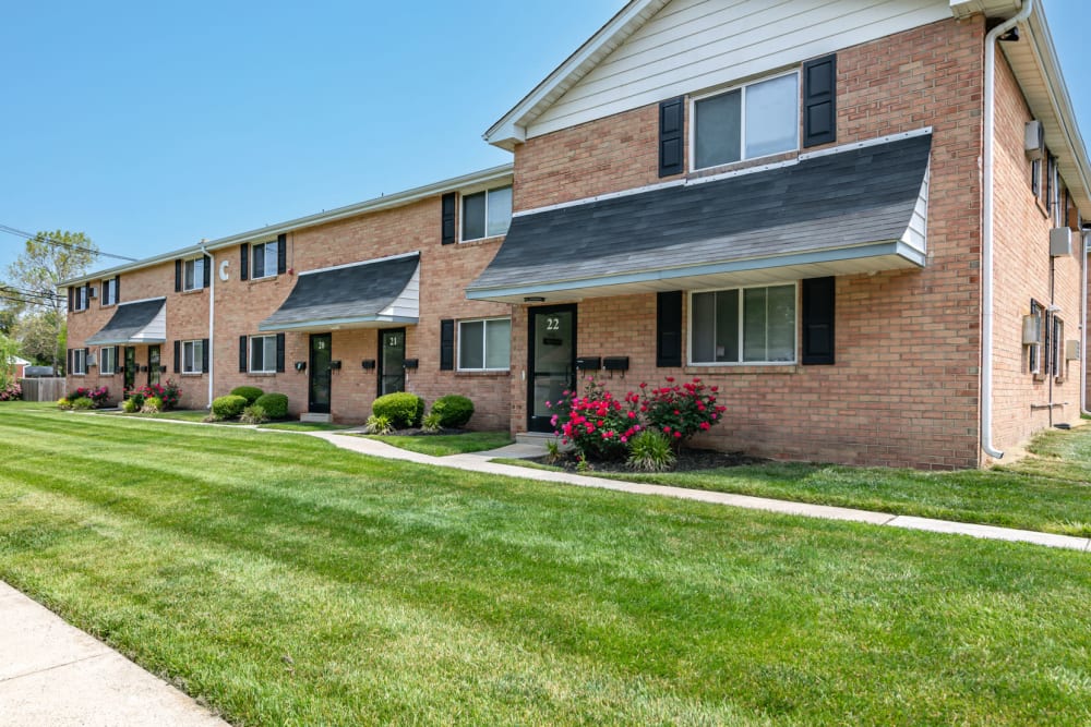 Red brick buildings with sidewalks and green grass at Warwick Terrace Apartment Homes in Somerdale, New Jersey