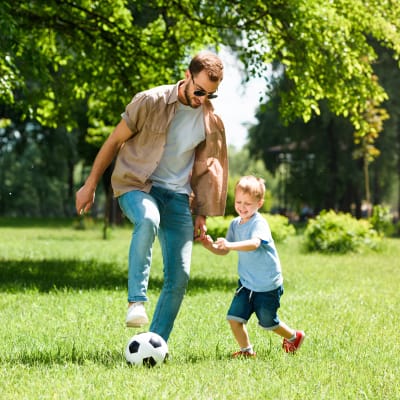 Father and son playing soccer in a park near Motif Apartments in Lynnwood, Washington