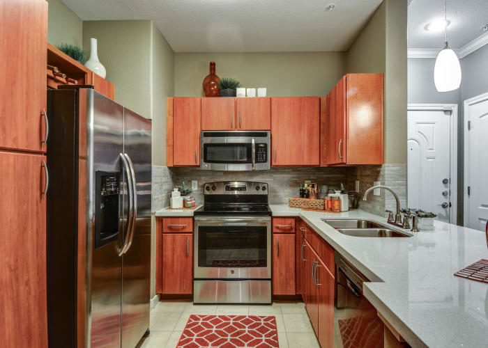 Gourmet kitchen with cherry wood cabinetry and stainless-steel appliances in model home at San Paloma Apartments in Houston, Texas