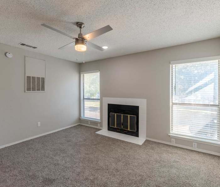 Unfurnished bedroom with ceiling fan, fireplace and carpet flooring at Park Place Townhomes in Euless, Texas