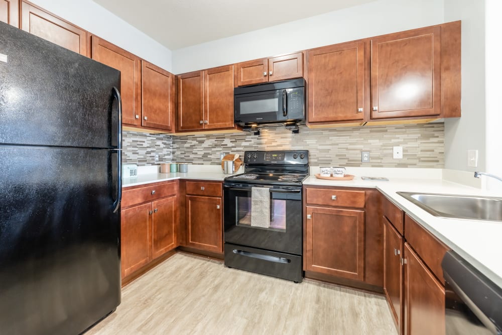 Kitchen with espresso cabinets and black appliances at Villa Capri Apartments in Rochester, New York
