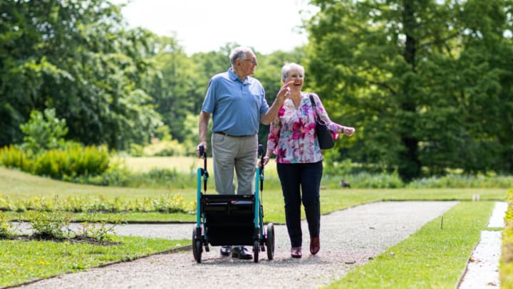 Two seniors walking outside with a walker