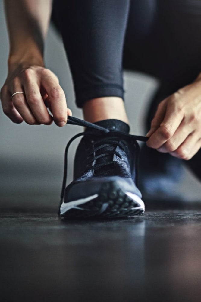 Resident tying her shoe in the fitness center at 55 Brighton at Packard Crossing in Boston, Massachusetts