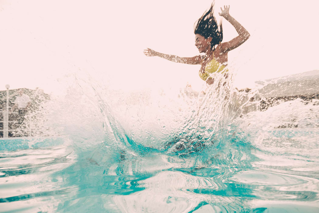 Woman jumping in the pool at The Phoenix Apartments in El Paso, Texas