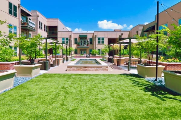 Courtyard at an independent living facility featuring lush green plants and a central fountain, offering a peaceful outdoor space for residents to relax.