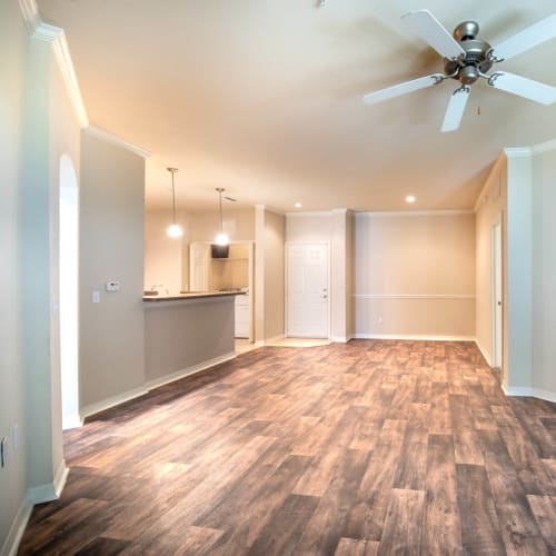 Large open-concept living area with hardwood flooring and a ceiling fan in a model home at Mirador & Stovall at River City in Jacksonville, Florida