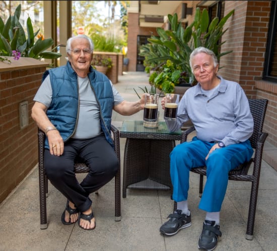 Residents sitting outside on the patio at Merrill Gardens at Greenville in Greenville, South Carolina