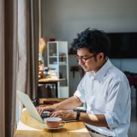 A man using his laptop at a table in his apartment at Mode at Hyattsville in Hyattsville, Maryland